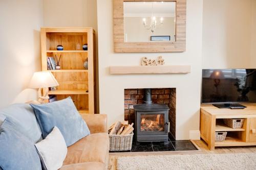 a living room with a fireplace and a couch at Northern Hideaways, Darling Cottage in Seahouses