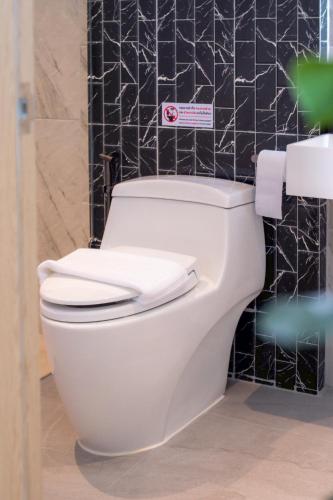 a white toilet in a bathroom with black tiles at Hello Teepak A34 in Ban Bo Prakhon