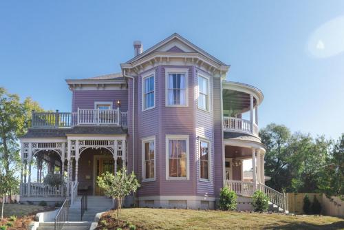 a large purple house with a porch and a balcony at The Gilded Lady - The Cypress Suite in Pensacola