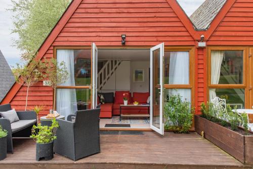 a red house with a red roof with a patio at Chalet 53 in Deal