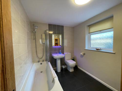 a bathroom with a tub and a sink and a toilet at Trout Cottage in Filey