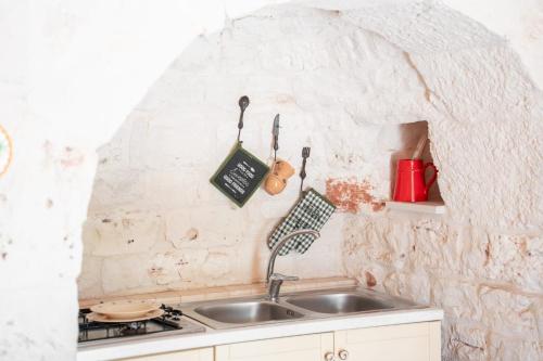 a kitchen with a sink and a stone wall at Trulli Beauty LAMIA family pool in Martina Franca