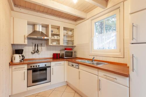 a kitchen with white cabinets and a sink and a window at Sekobbe 218 - Baabe in Baabe