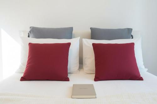 a bed with three red pillows and a book on it at San Siro - 1st Studio & free wifi in Milan