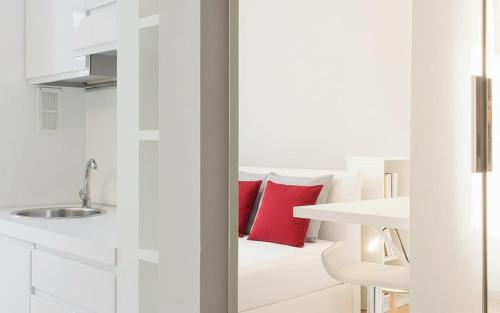 a white bathroom with a sink and a red pillow at San Siro - 1st Studio & free wifi in Milan