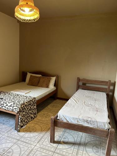a room with two beds and a chandelier at Suítes estrela dalva in Lauro de Freitas