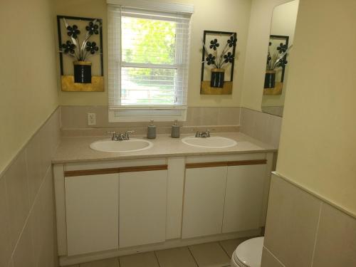 a bathroom with two sinks and a window and a toilet at The Taunton House in Ajax