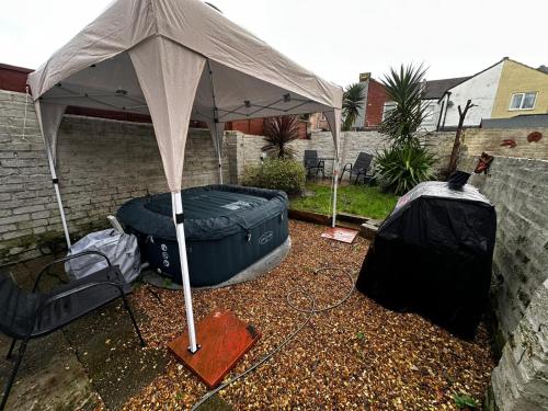 an umbrella over a tire and a tub in a yard at Open Mind Property - Hot Tub , Garden , 3 Bedroom in Portsmouth
