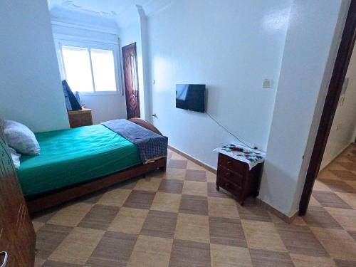 a bedroom with a green bed and a table at Martil Apartment Near Beachfront in Martil