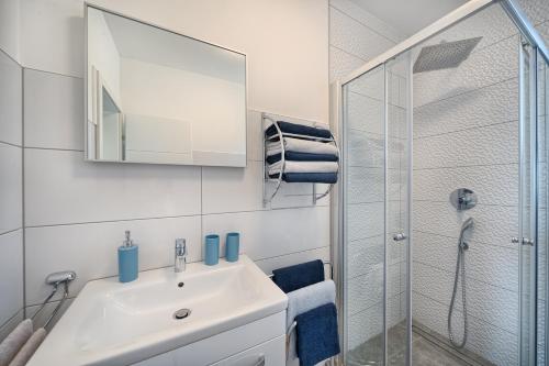 a white bathroom with a sink and a shower at Petra's Place - Sea view apartment in Slatine