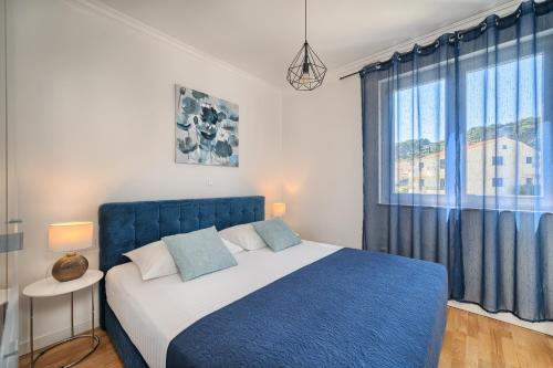 a bedroom with a blue bed and a window at Petra's Place - Sea view apartment in Slatine