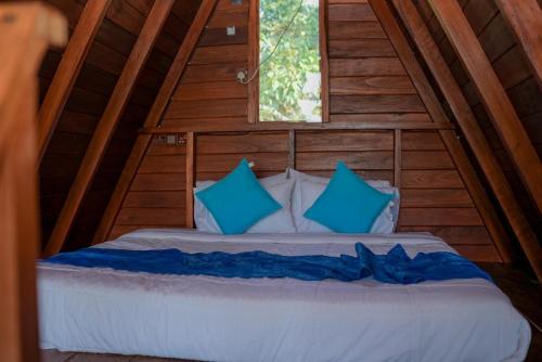 a bed in a wooden cabin with blue pillows at Gimanhala Thisawewa in Anuradhapura