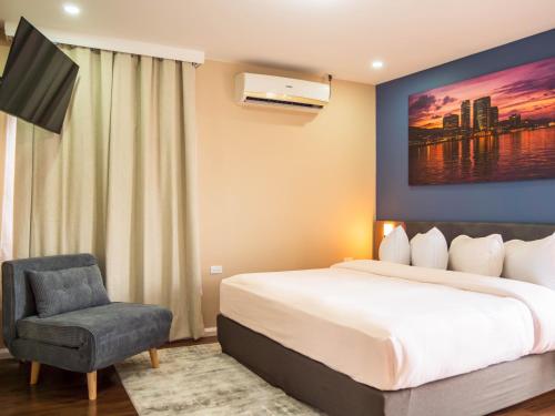 a hotel room with a bed and a chair at TStays Smart Hotel Courtyard, Gated Modern Stay in Port-of-Spain