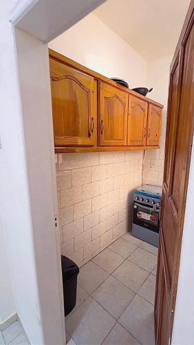 mała kuchnia z drewnianymi szafkami i kuchenką w obiekcie PKanyi's w mieście Serekunda