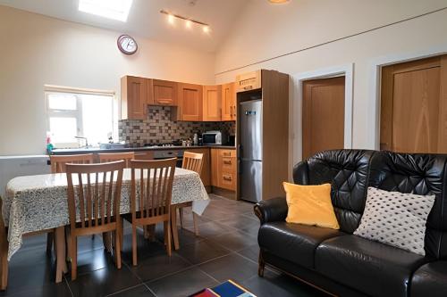 a kitchen with a table and a black leather couch at Nancy's Seaside Cottage, Renvyle in Renvyle