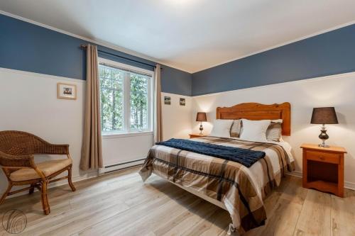 a bedroom with a bed and a chair and a window at Condo Lac Archambault Fireplace beach in Saint-Donat-de-Montcalm
