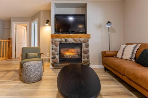 a living room with a fireplace with a tv above it at Riverside Condos by Fernie Central Reservations in Fernie