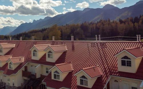 a row of houses with red roofs with mountains in the background at Riverside Condos by Fernie Central Reservations in Fernie