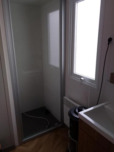 a bathroom with a shower with a window and a sink at Location mobil home in Litteau