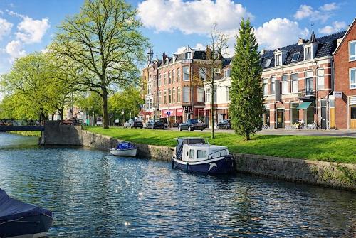 two boats are docked on a river in a city at Canal House Haarlem in Haarlem