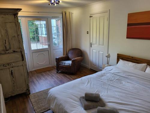 a bedroom with a bed and a chair and a window at Little Brookfield in Lymington