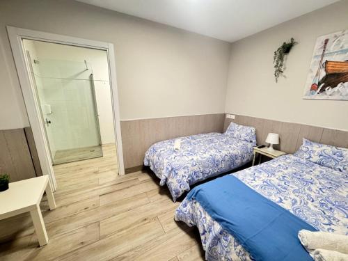 a bedroom with two beds and a walk in shower at Albergue Logroño Centro in Logroño