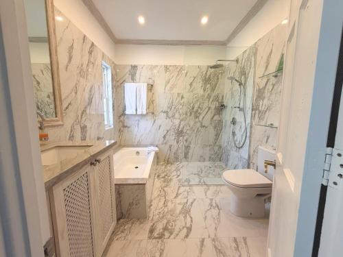 a bathroom with a toilet and a tub and a sink at Coconut Grove 1, Luxury Villa by Island Villas in Saint James