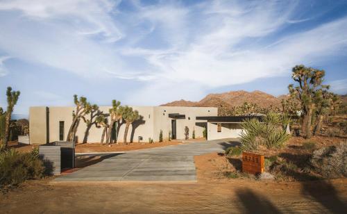 a white building in the middle of the desert at Pool - Spa - Fire pit - Views - BBQ - Bella Nova in Joshua Tree