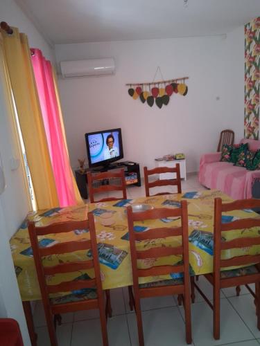 a dining room with a table and chairs and a television at charmante maison in Les Avirons