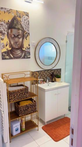 a bathroom with a statue on the wall and a sink at Villa Eden hibiscus in Petit-Canal