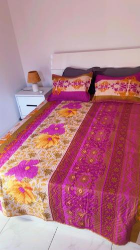a bedroom with a bed with a colorful comforter and pillows at Villa Eden hibiscus in Petit-Canal