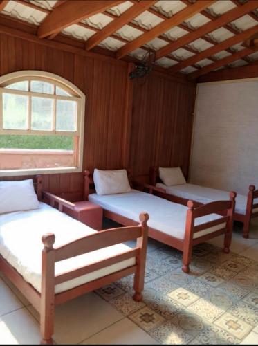 two beds in a room with a window at Chalé Manancial in Socorro