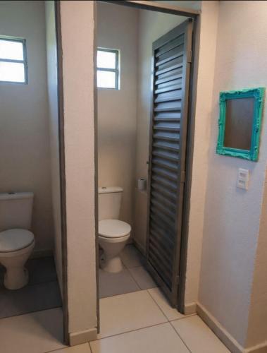 a bathroom with a toilet and a door with a window at Chalé Manancial in Socorro