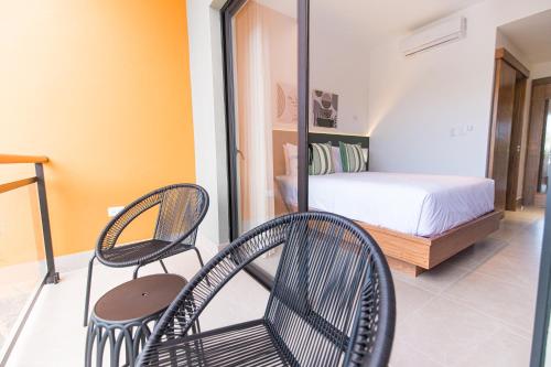 a bedroom with two chairs and a bed in it at PF Hotel in San Felipe de Puerto Plata