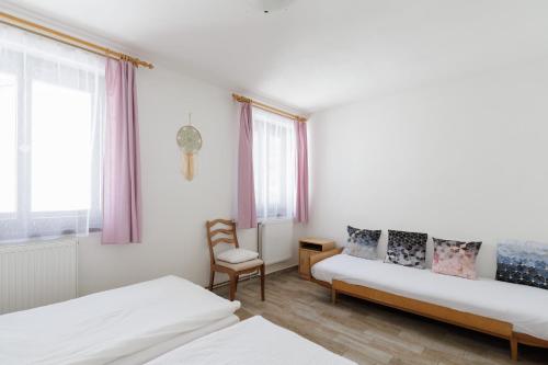 a bedroom with two beds and a chair and windows at Chalupa U Lávky in Lasenitz