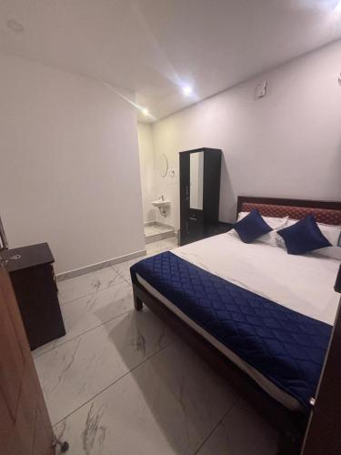 a bedroom with a bed with blue sheets and blue pillows at Mount Elbrus Home stay in Devikolam