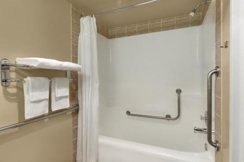 a bathroom with a tub and a shower with towels at Colonial Square Inn & Suites in Saskatoon