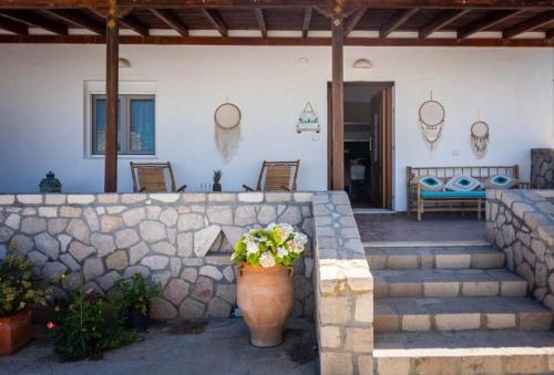 a patio with a stone wall and a vase of flowers at SunΚissed Home - Pollonia Milos in Pollonia
