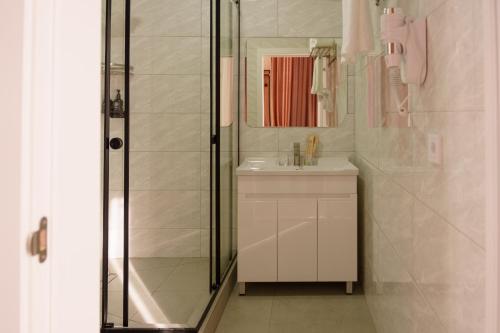 a white bathroom with a shower and a sink at Ton Azure Hotel in Tong