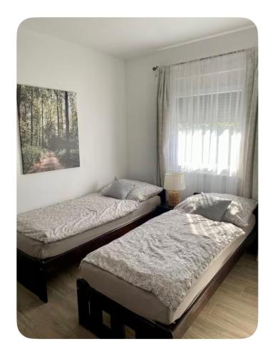 two beds sitting in a bedroom with a window at Riverside Home Szigetköz in Dunasziget