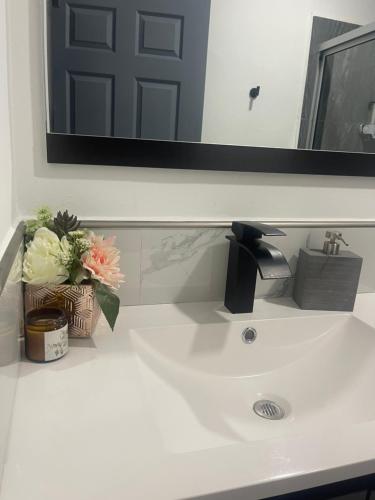 a bathroom sink with a mirror and flowers on it at The Bello Lodging B in Sonsonate