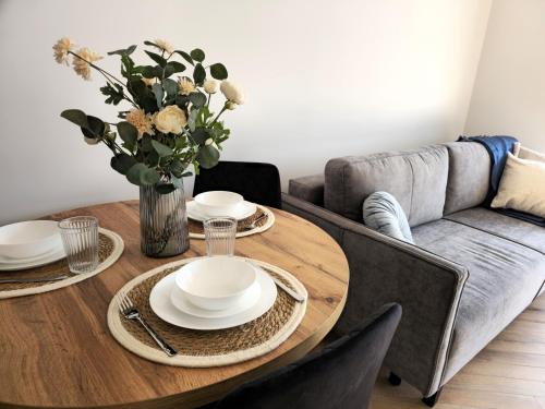 a dining room table with plates and a vase of flowers at Borki Lake View Apartment in Radom