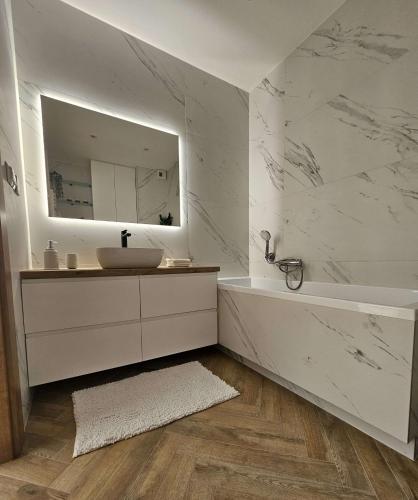 a bathroom with a sink and a tub and a mirror at Borki Lake View Apartment in Radom