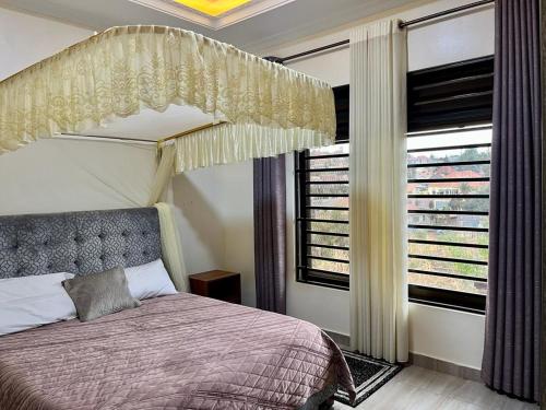 a bedroom with a canopy bed and a window at Quiet Home Apartment in Kigali