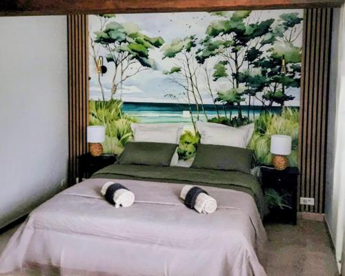 two beds in a bedroom with a painting on the wall at La Cour d'Arblade in Arblade-le-Haut