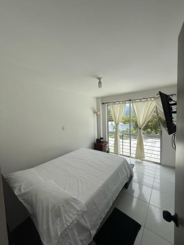 a bedroom with a white bed and a large window at Cozy house in Dosquebradas in Dosquebradas