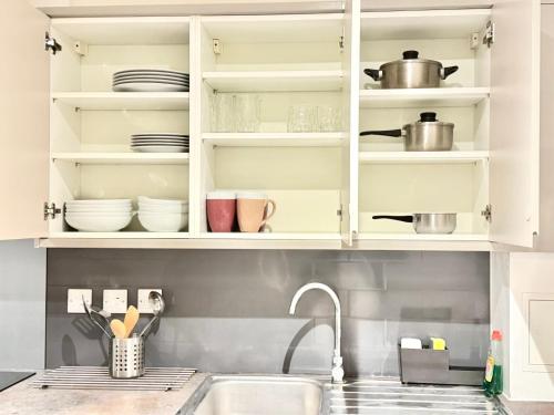 a kitchen with white cabinets and a sink at Hampton Suites Serviced Apartments in Kingston upon Thames