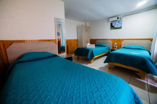a bedroom with two beds with blue comforters at Hotel Montecarlo in Caldera