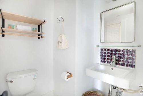 a white bathroom with a sink and a mirror at The Windrose in Savannah
