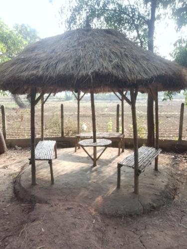 two benches sitting under a thatched umbrella at CHAYAA BITHII Resort & Restaurant in Kopāi